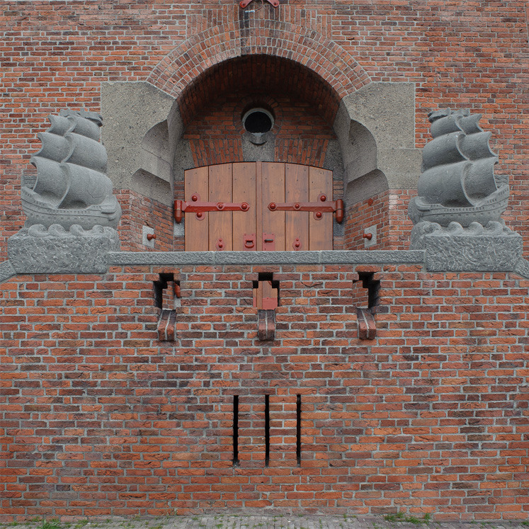 Historische Backsteinmauer mit hölzerner Doppeltür und steinernen Schiffsverzierungen.