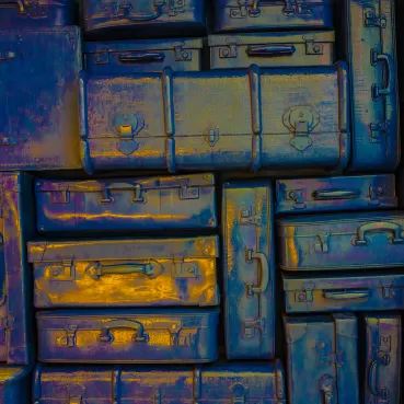 Stapel aus blauen und goldfarbenen Metallkoffern mit reflektierenden Oberflächen