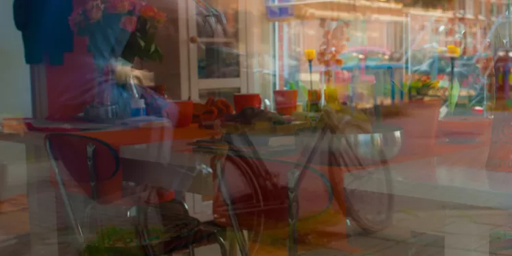 Künstlerische Spiegelung einer Café-Innenszene mit Tisch, Stühlen und Dekoration im Fenster